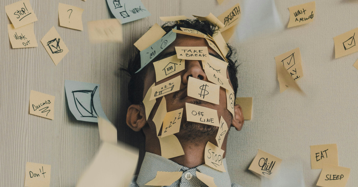 Young man covered in sticky notes, work overload